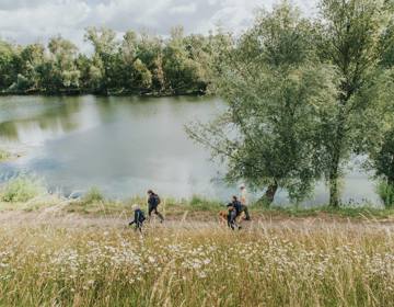 Een groepje mensen wandelt langs de Maas door Rivierpark Maasvallei
