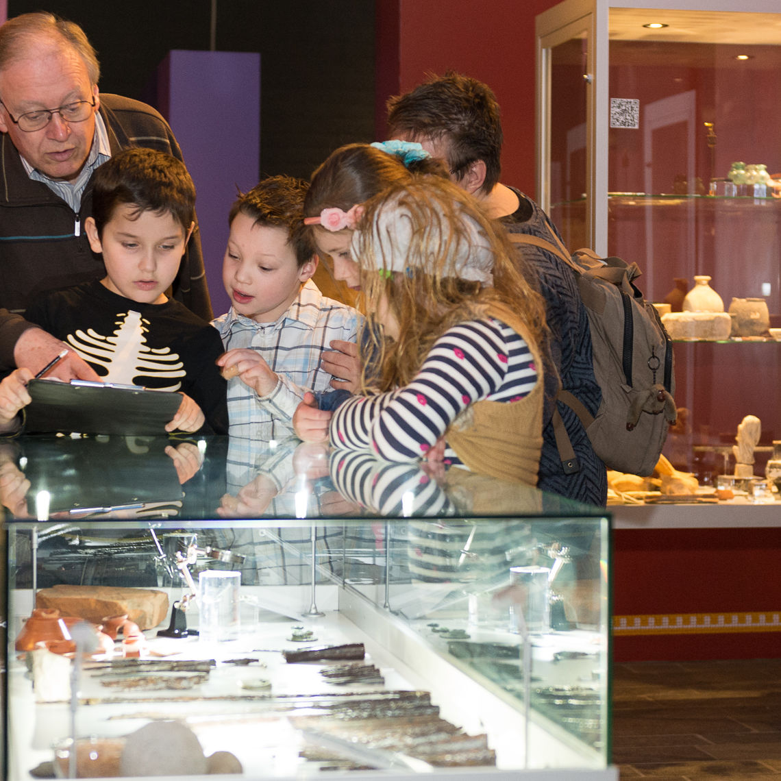 Kinderen en oudere meneer bekijk overblijfselen van de Romeinse tijd in het museum De Vondst