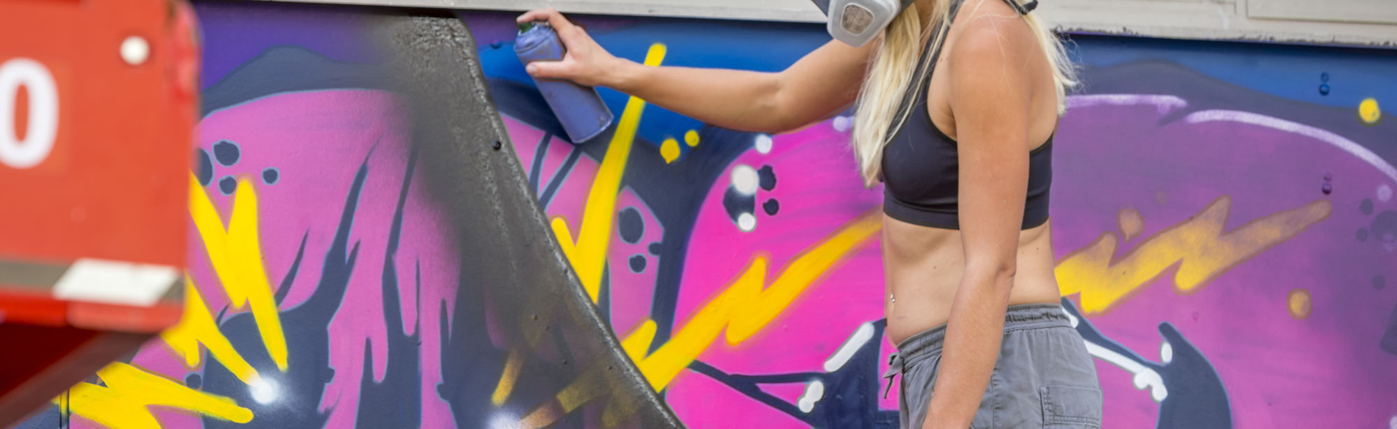 Vrouw die graffiti spuit op de Quatro bioscoop in Heerlen