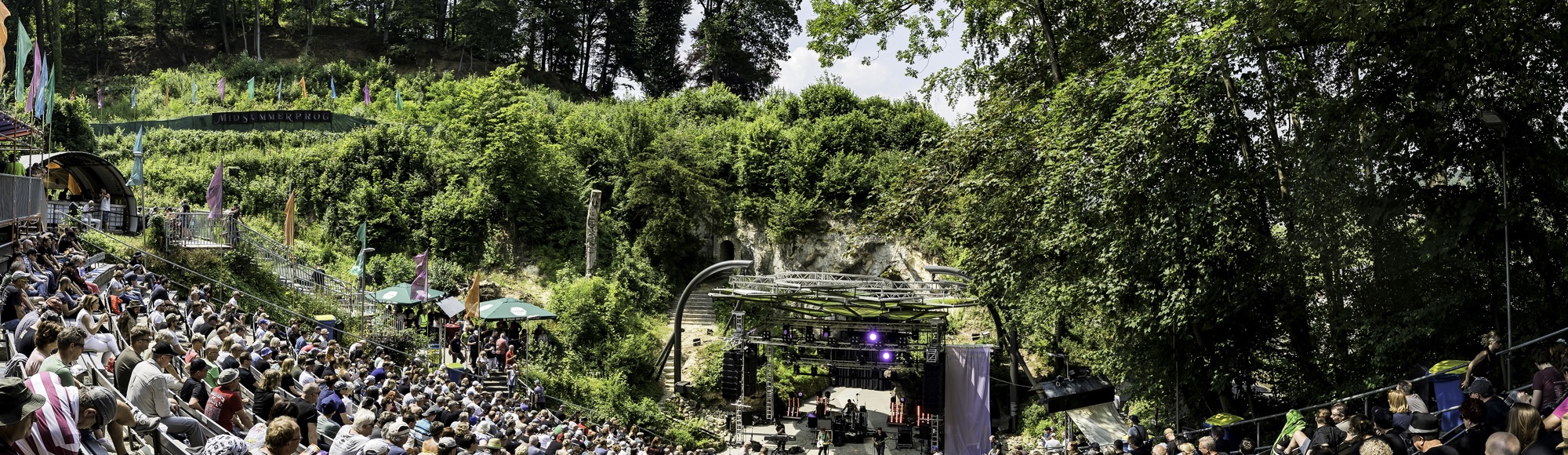 Overzichtsfoto van publiek en podium bij openluchttheater Valkenburg op zonnige dag