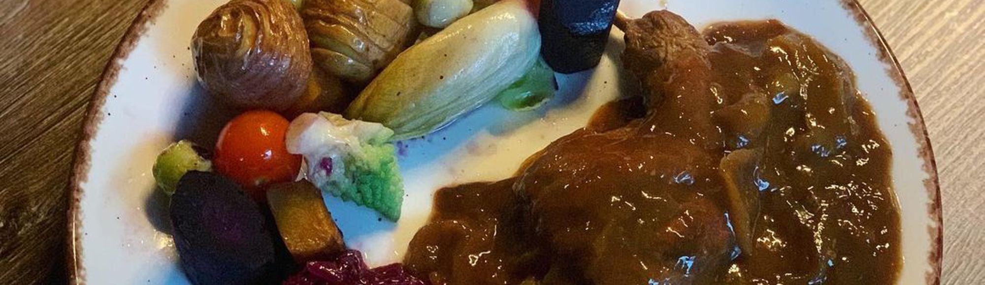 Limburgse Knien in 't Zoer op een bord, geserveerd met aardappel, rode kool en diverse groenten.