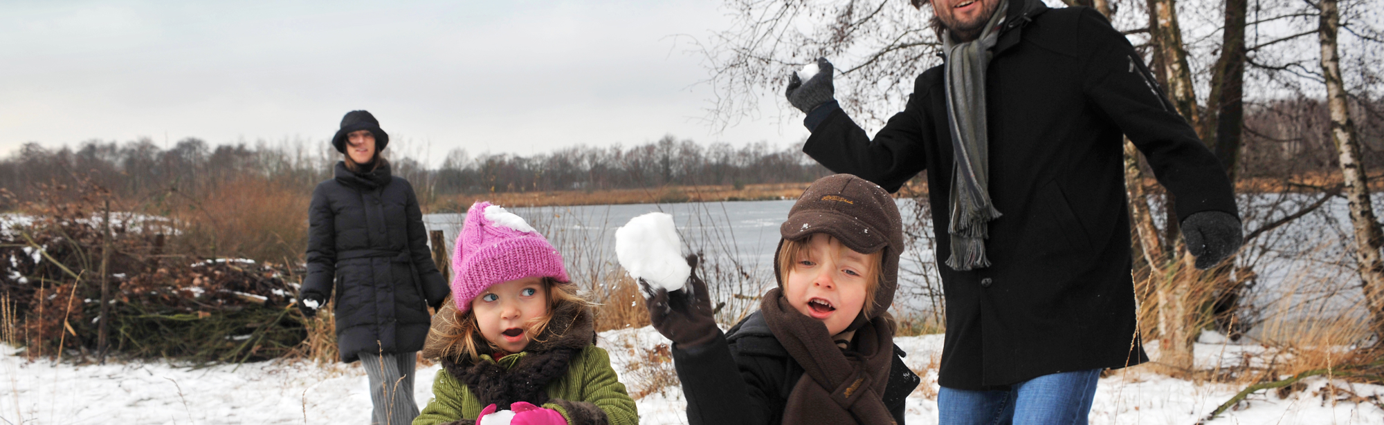 Ouders met twee kinderen gooien met sneeuwballen richting de camera