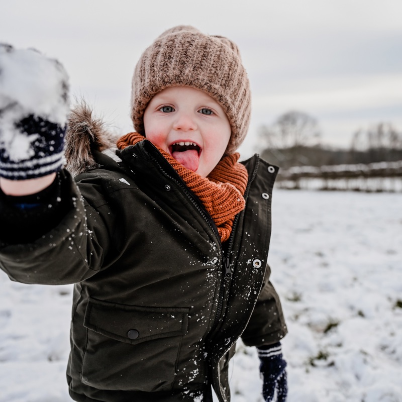 Ondeugend jongetje gooit een sneeuwbal richting de camera
