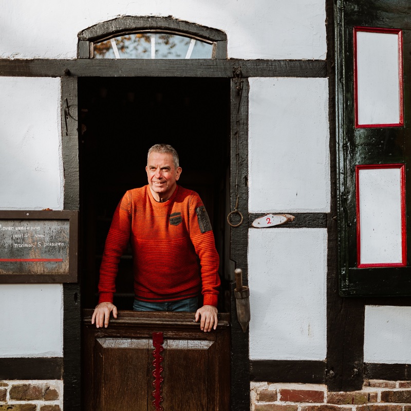Een man kijkt door een oude deurpost vanuit het vakwerkhuis naar buiten
