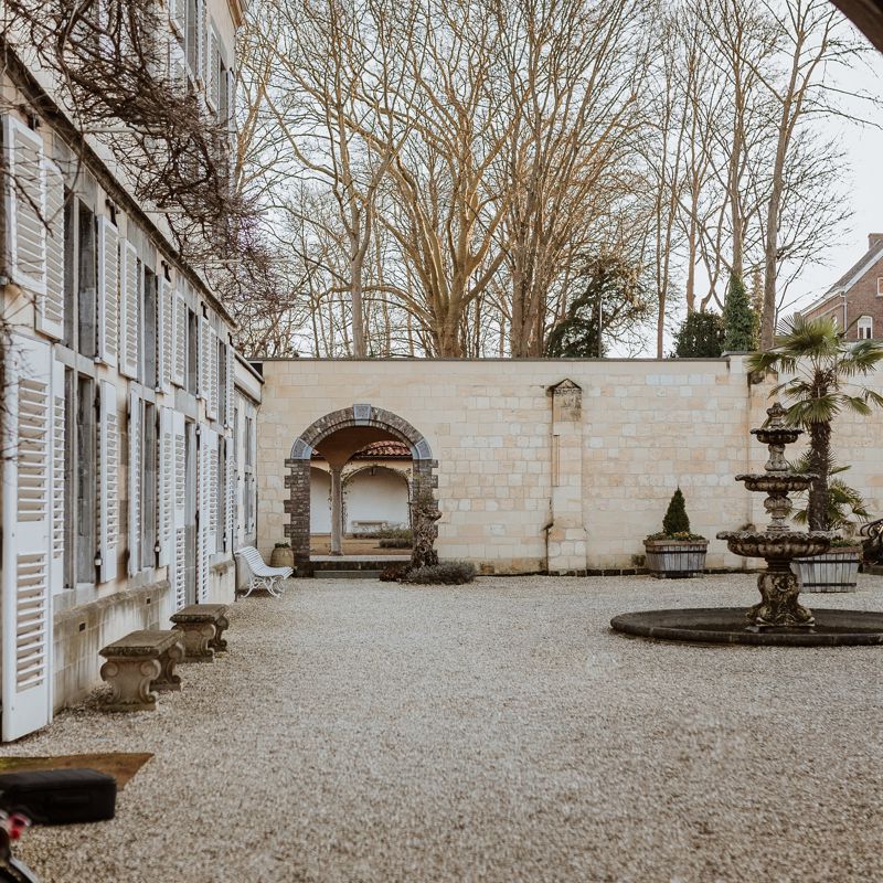 Binnentuintje van André Rieu met kiezels, Romeinse bogen, een fonteintje en palmboom