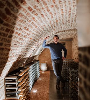 Maurice Warnier poseert in een gewelfde wijnkelder