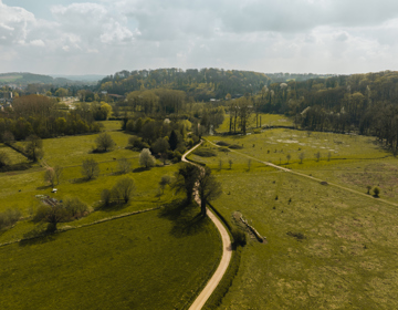 Een kronkelweg leidt je door een groen landschap