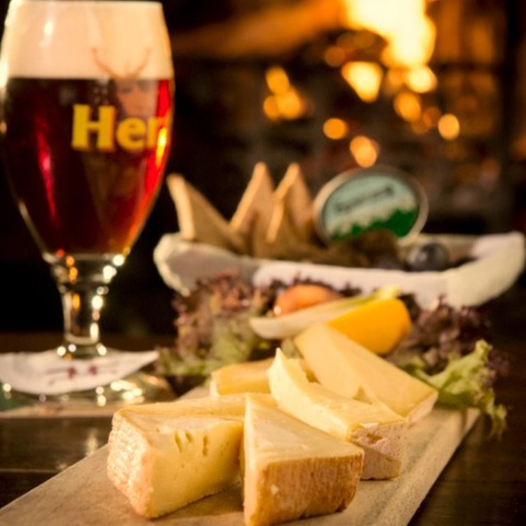 Verse streekproducten en een winters biertje op tafel uitgestald voor een verwarmend haardvuurtje