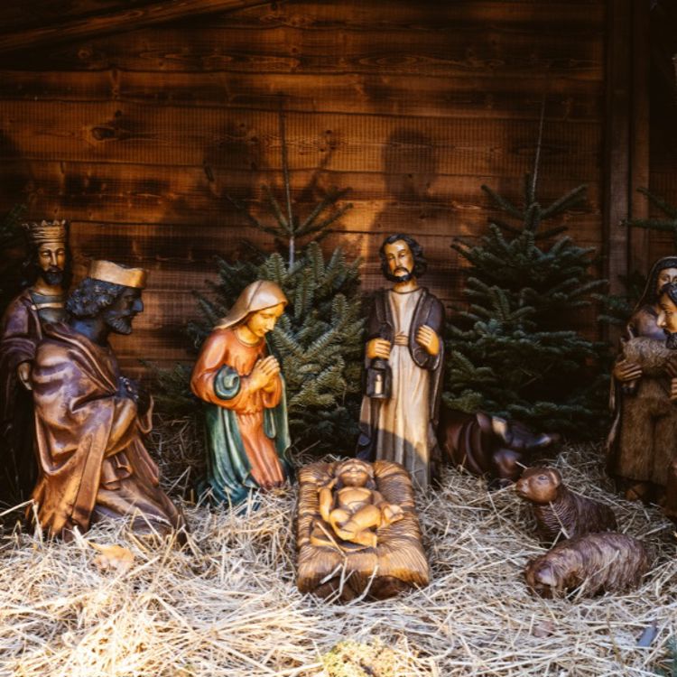 Een sfeervolle kerststal met heiligenbeelden, stro en kerstbomen