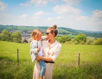 Moeder houdt meisje in de armen in zuid-limburgse heuvelland. 