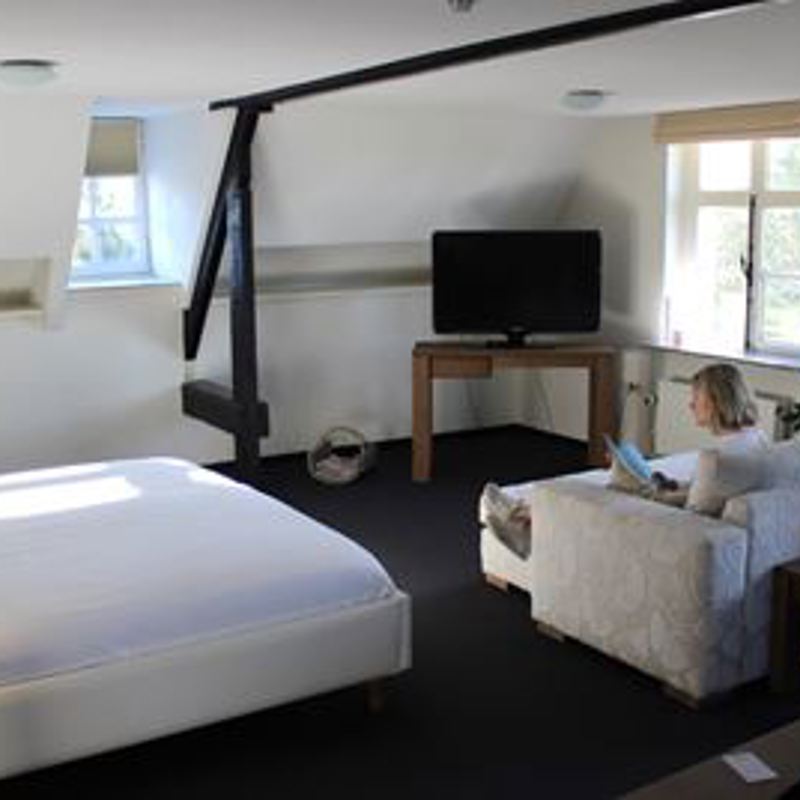 Een vrouw zit op de bank in de bruitssuite van Kasteel Doenrade