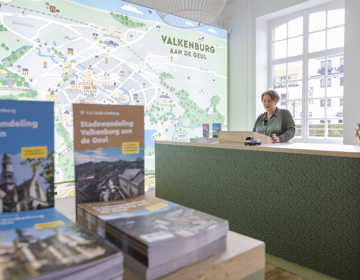 Folders in de Visit Zuid Limburg Experience met de frontoffice medewerker achter de balie