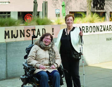 Foto Inclusie Audioroute Heerlen, twee dames, een in een elektrische rolstoel en een met een blinde stok