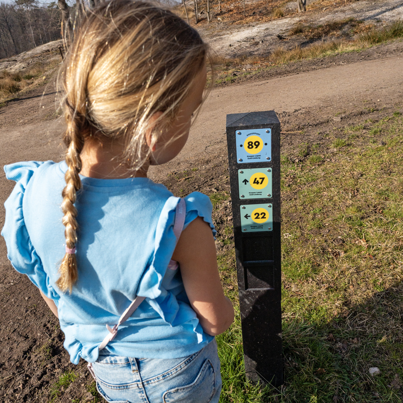 Meisje bekijkt knooppuntenpaal van dichtbij.