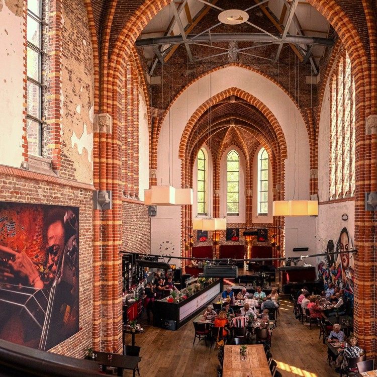 Brasserie Abshoven kerk interieur met mensen die gezellig eten aan tafels in oude kerk als religieus erfgoed