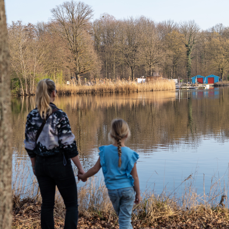 Moeder en dochter kijken hand in hand naar de vijver.