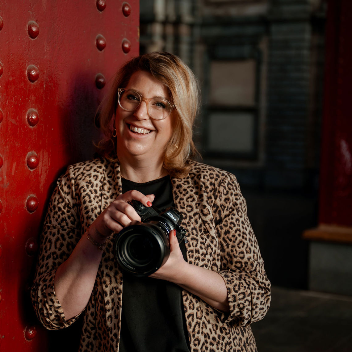 Fotografe Sanne staat in een deuropening en heeft haar camera vast in haar hand 