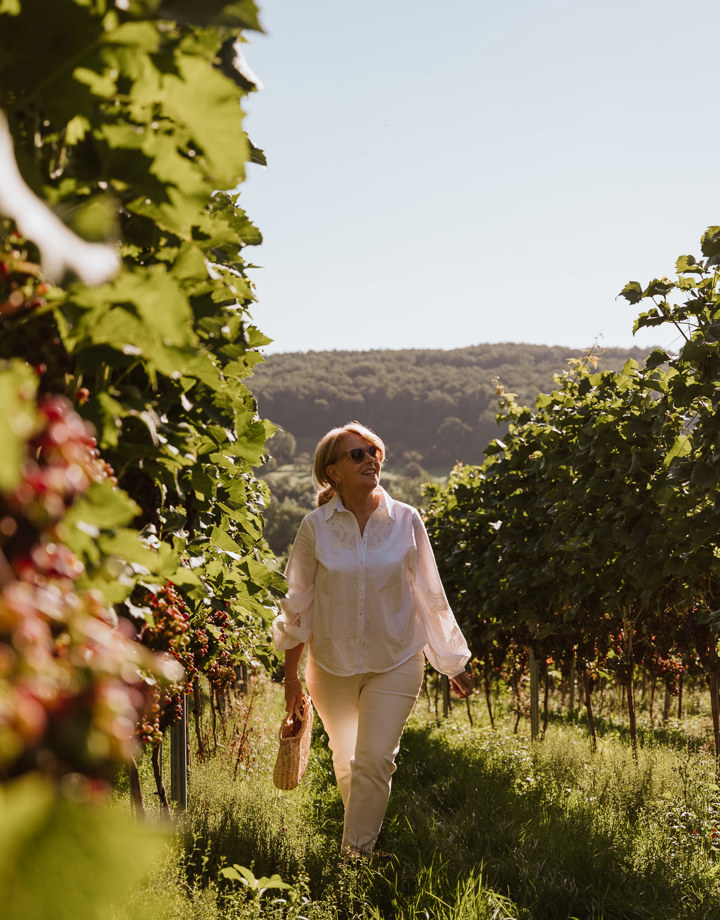 Een wat oudere dame wandelt door de wijnstokken in Slenaken en geniet van het goede leven