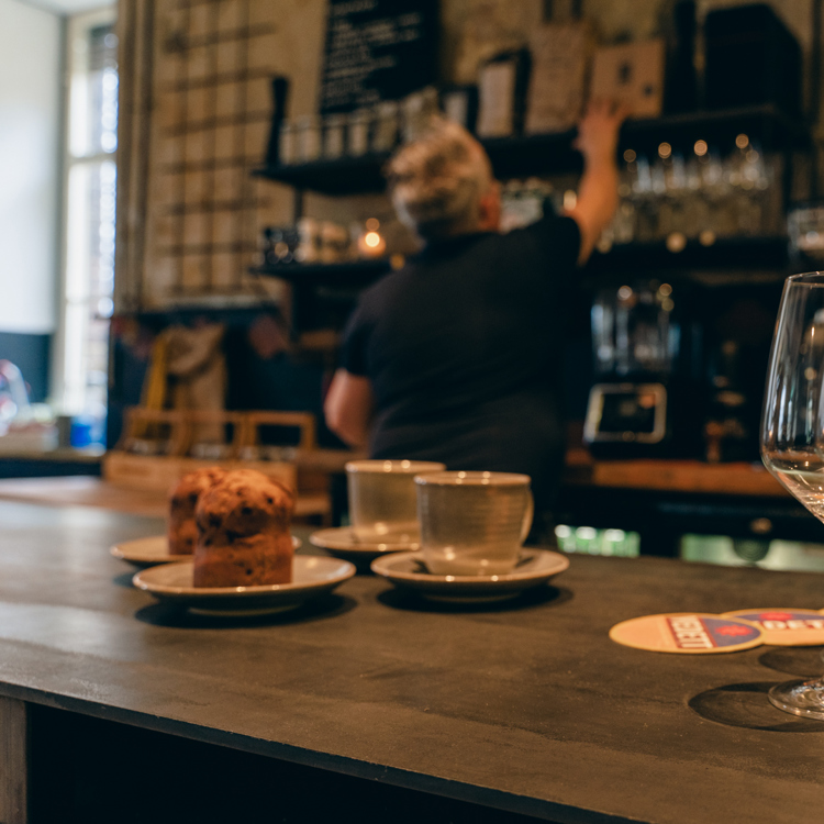 Bar met koffie en wijn met op de achtergrond een medewerker bij de koffieautomaat.