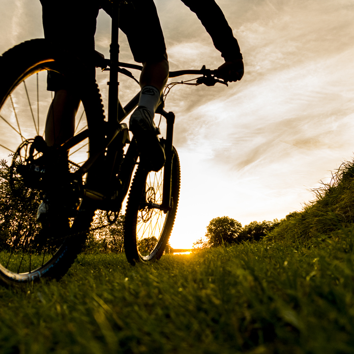 Mountainbiker fietst door het landschap met zonsondergang op de achtergrond