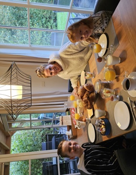 Een moeder en twee kleine kinderen zitten aan tafel van hun vakantiehuisje voor een lekker ontbijtje