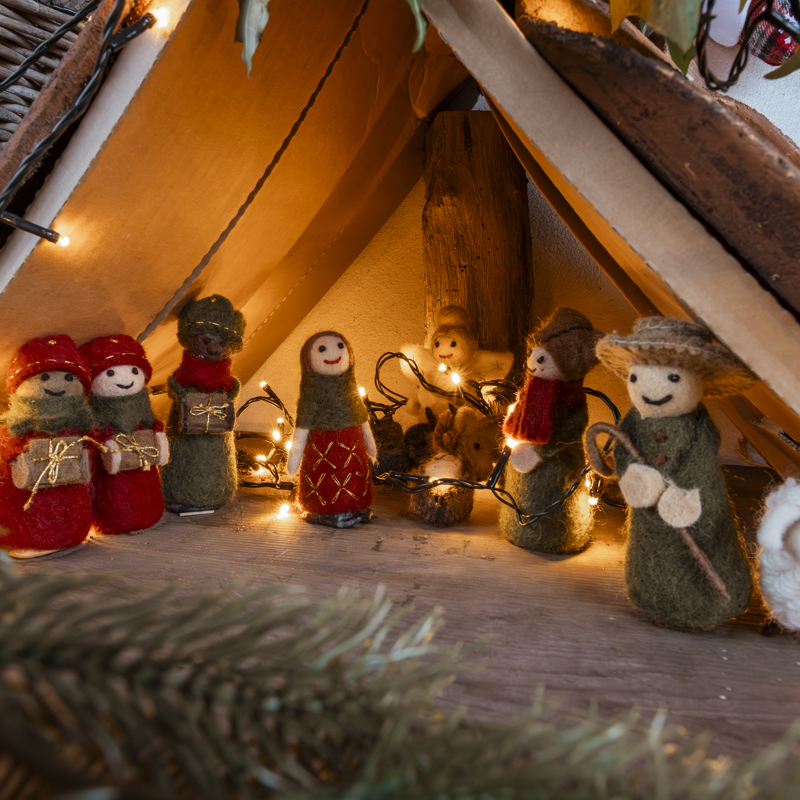 Miniatuur kerstpoppetjes onder miniatuur dakje met kerstlampjes