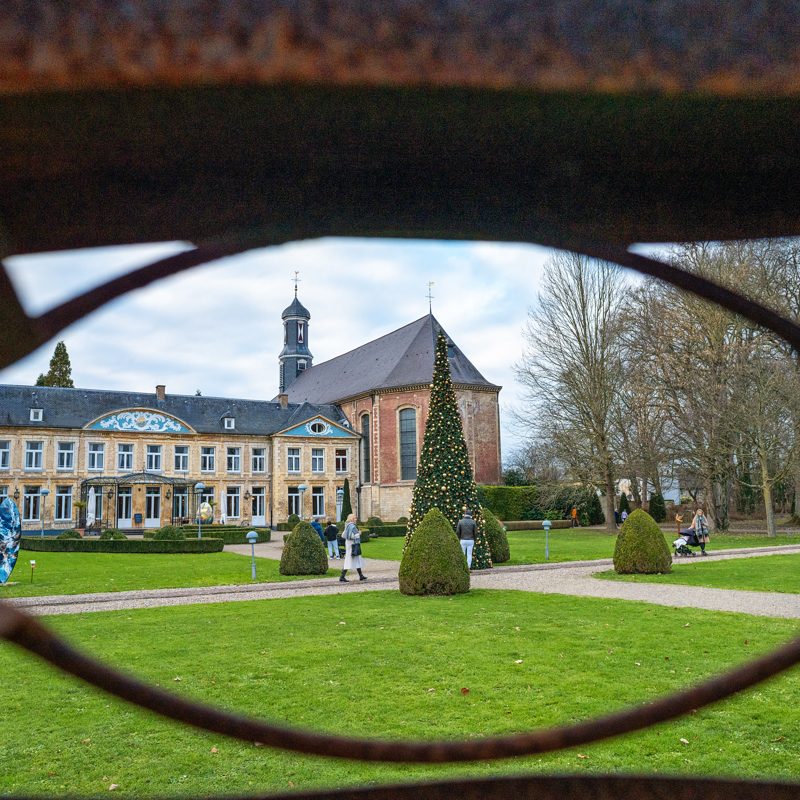 Kerk bekeken door kijkgat in hek met kerstboom