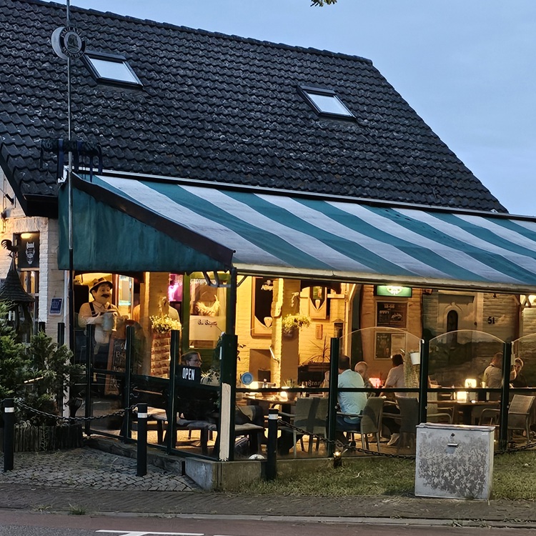 Mensen op een terras onder een gestreepte luifel van café brigitte in Urmond
