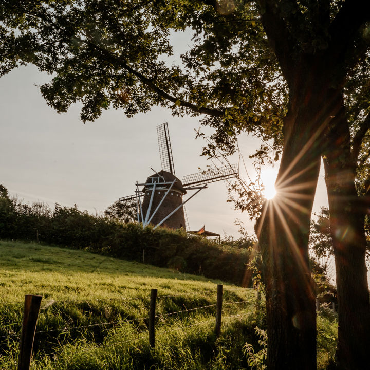 Zijkant van een molen en een laagstaande zon in Voerendaal.