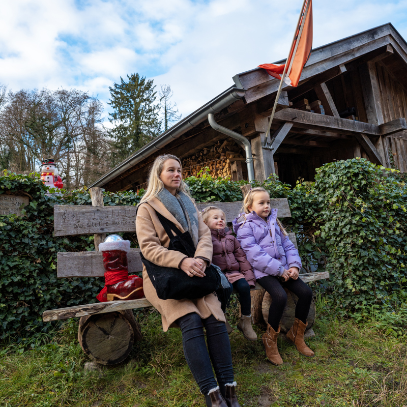 Vrouw en twee kinderen zittend op bankje in de winter
