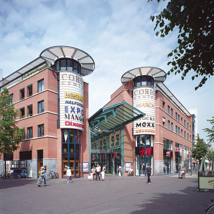 Mensen die winkelen door een winkelgebied met hoge gebouwen en merknamen op de gevel