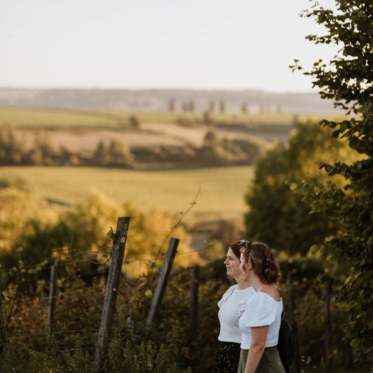 Twee meisjes in zomerse kleren kijken uit over wijngaard Aldenborgh in Eys