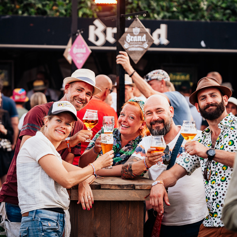 Een groepje mensen op Pinkpop die genieten van een limited edition Brand bier