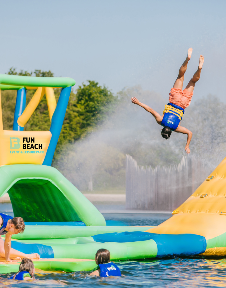 Kind vliegt door de lucht op aquapark op natuurwater.