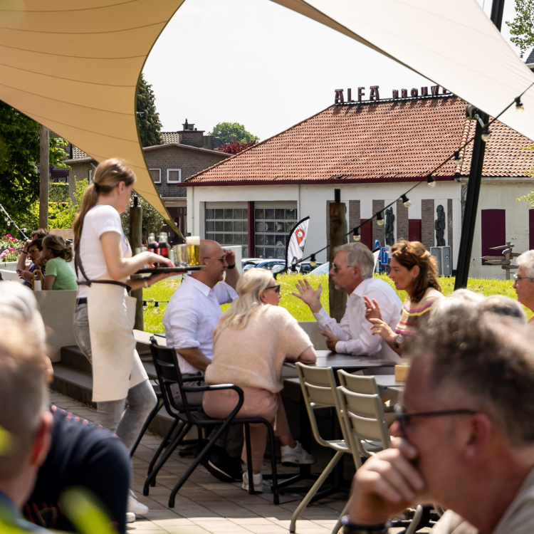 Mensen en bediening op het terras van het brouwerijcafé van alfa in de zon en drinken bier
