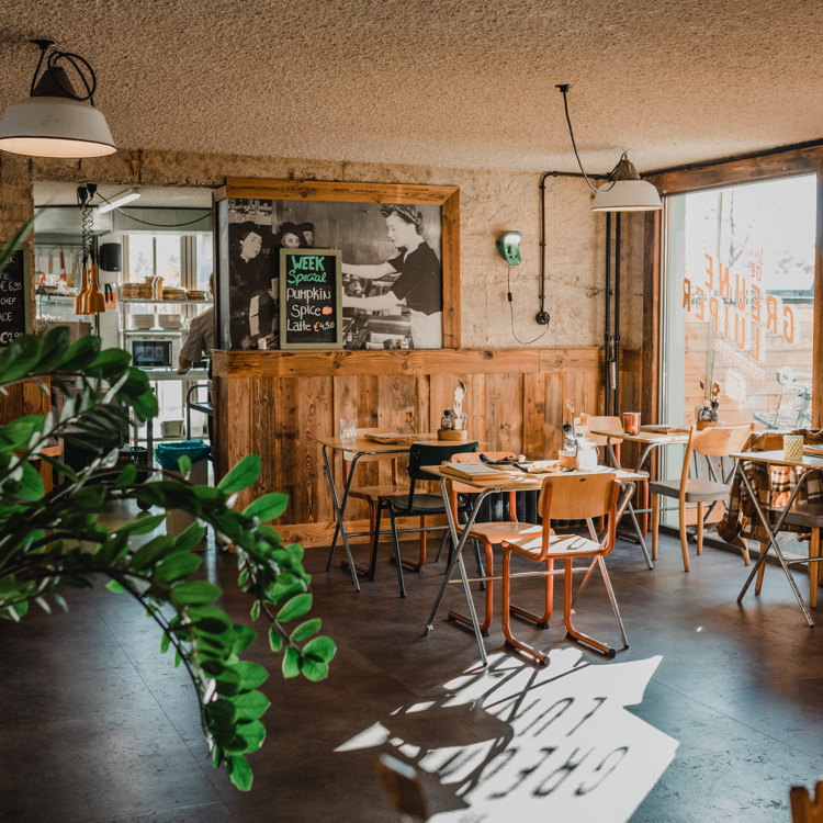 Interieur van gezellige koffietentje met veel hout en planten.