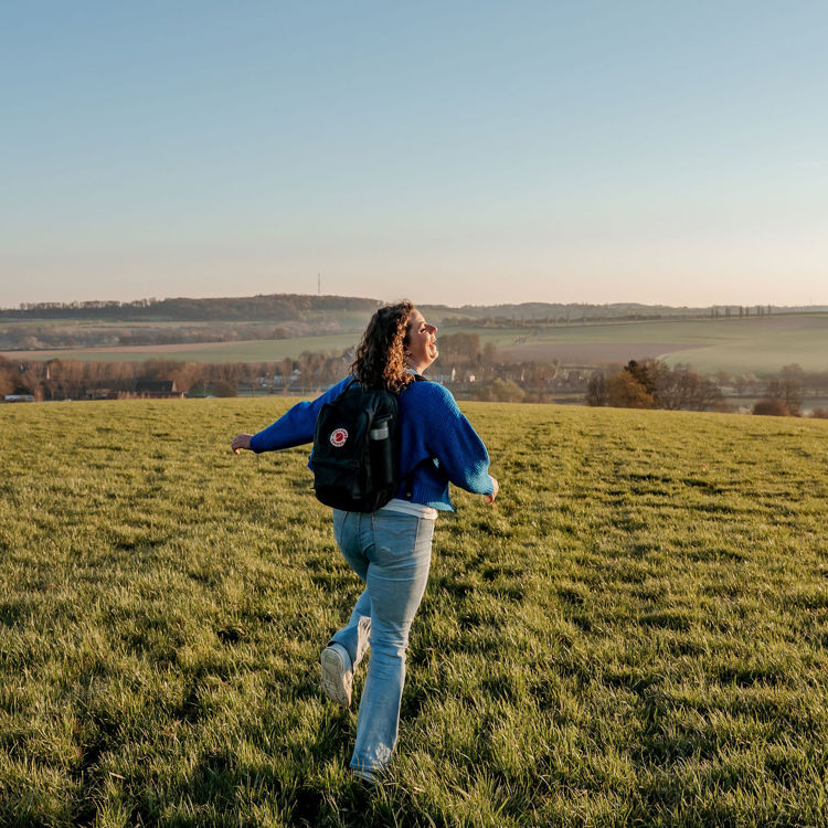 meisje huppelt vrolijk door Zuid-Limburg met een weids uitzicht op de achtergrond.