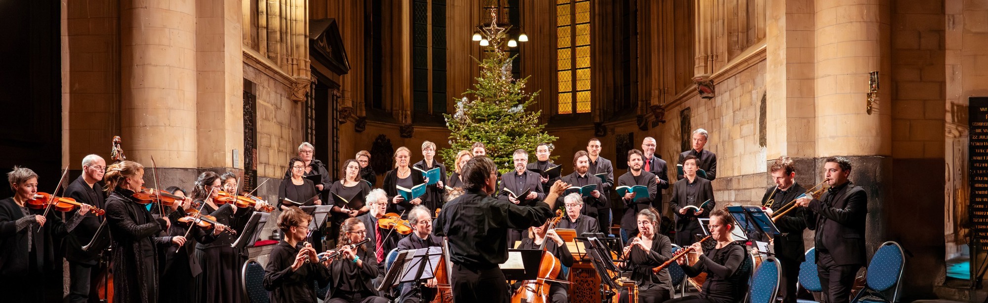 Orkest in een kerk met kerstboom op de achtergrond