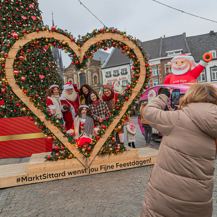 Mensen geposeerd in levensgroot hart voor foto met kerstversiering