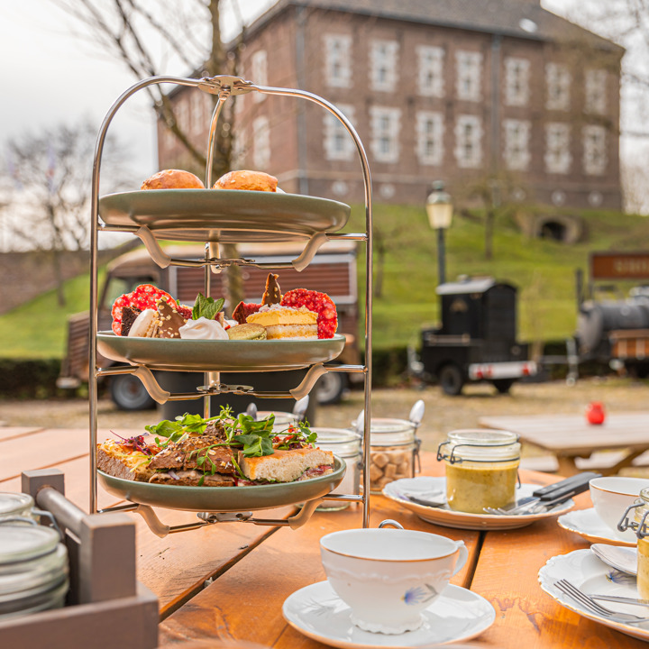 Tafel met uitgestalde high-tea op de binnenplaats van Kasteel Limbricht.