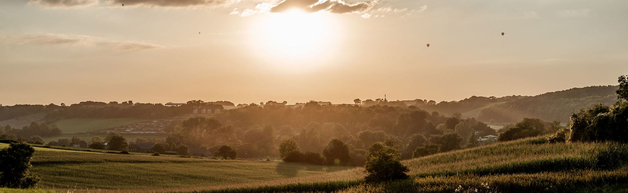 Weilanden, heuvels en ondergaande zon nabij Gulpen 