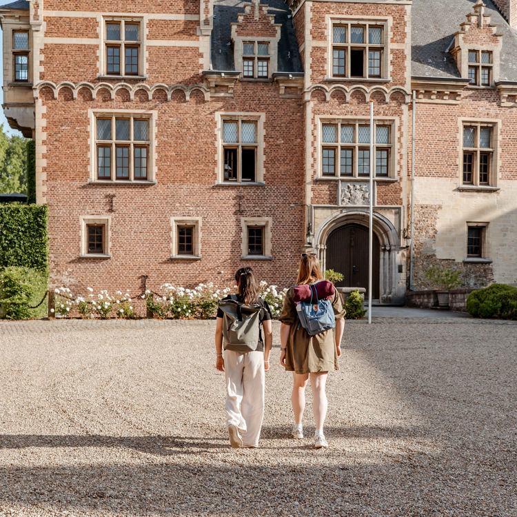 Twee wandelaars in zomerkleding wandelen door de zon bij kasteel mheer met een rugzak
