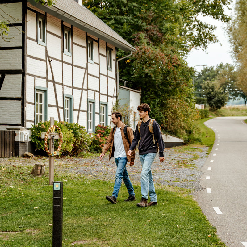 Twee jonge mannen lopen voor langs een vakwerkhuis
