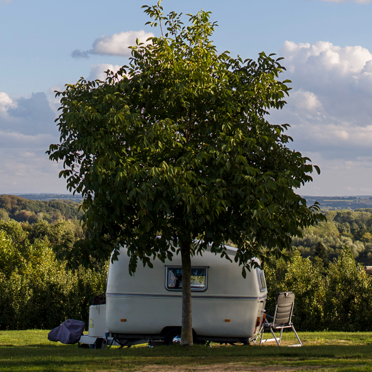 Een caravan op een camping met uitzicht over het heuvelland en zon