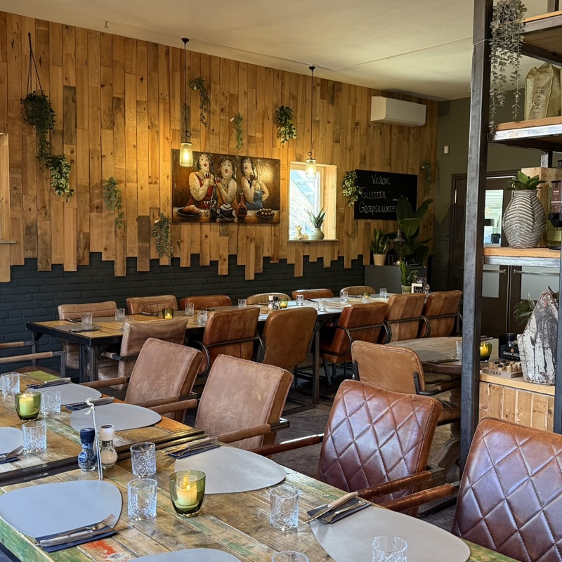 Interieur van een horecazaak Biej de tant, met gedekte tafels. 