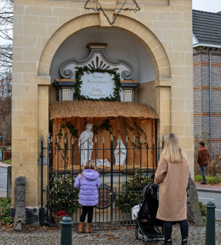 Vrouw met kinderen kijkend naar Kerstkribke Wandering Dutchies