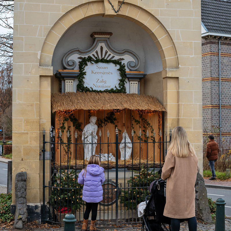 Vrouw met kinderen kijkend naar Kerstkribke