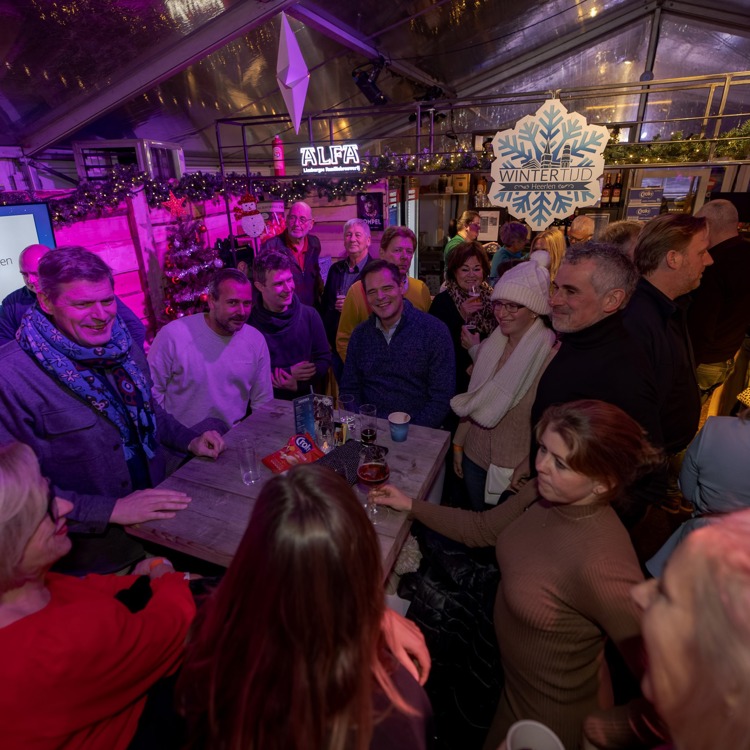Mensen in overdekte tent rondom een statafel met sfeerverlichting