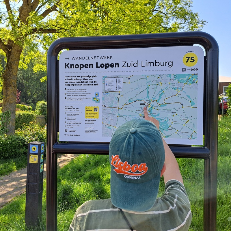 Jongetje wijst zijn locatie aan op een infobord van het Knopen Lopen wandelnetwerk.