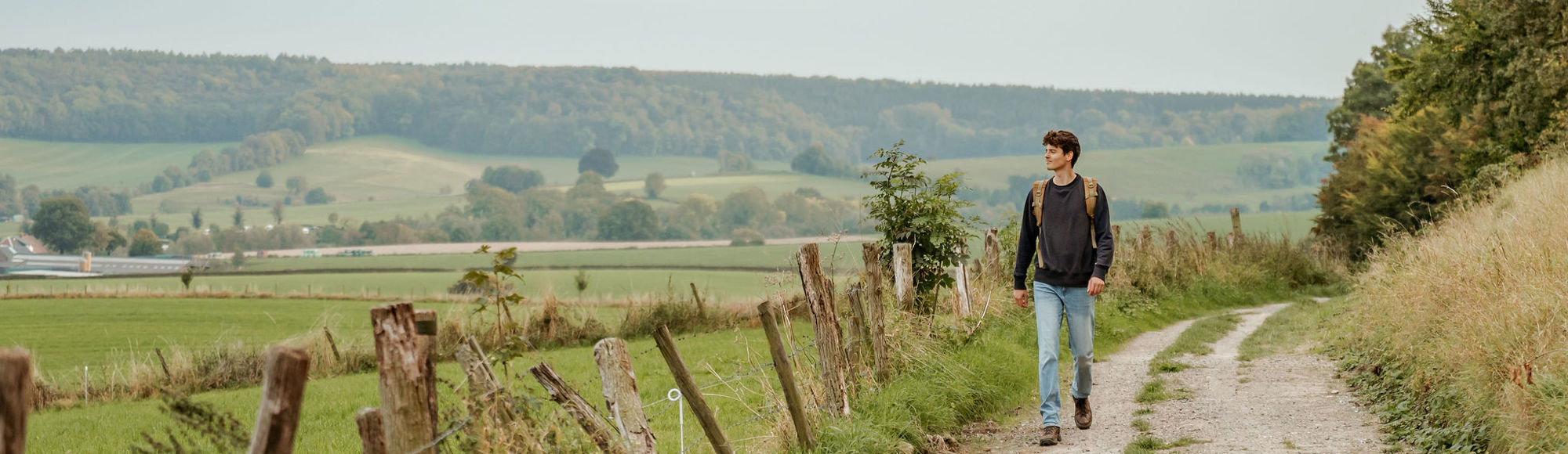 Een jonge man wandelt door een typisch Zuid-Limburgs landschap 